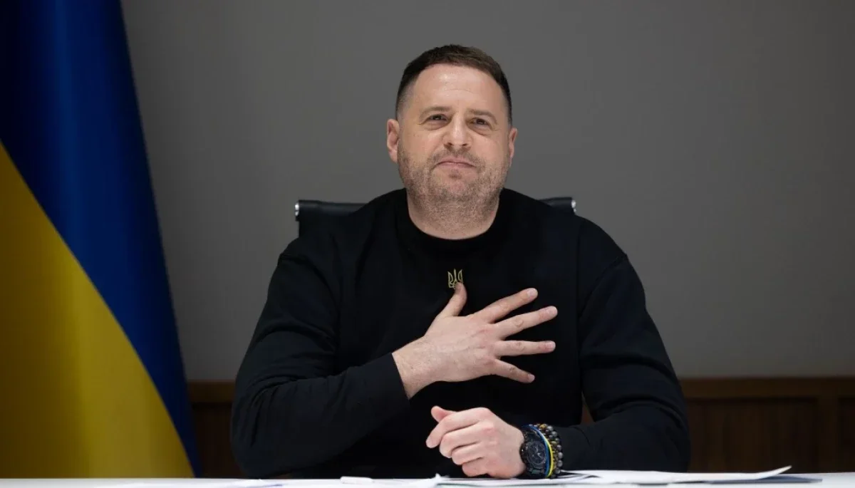 Игорь Фомин, адвокат Ермака, прикладывает руку к сердцу на фоне флага Украины