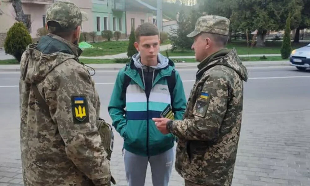 Співробітники ТЦК вручають повістку молодому чоловіку на вулиці Києва