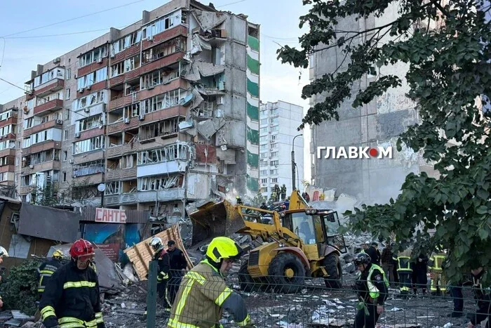 Рятувальники на екскаваторі розбирають завали багатоповерхівки в Дарницькому районі Києва після удару РФ.