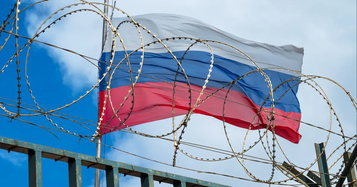 Прапор Росії за спіралями колючого дроту на тлі неба