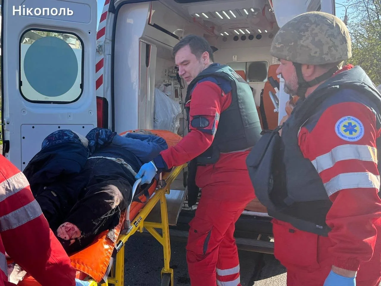 Парамедики завантажують пораненого в швидку після атаки дроном на Нікополь