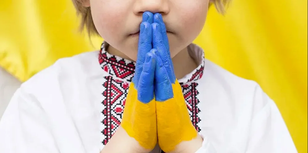 Українська дитина в вишиванці молиться за відновлення після війни