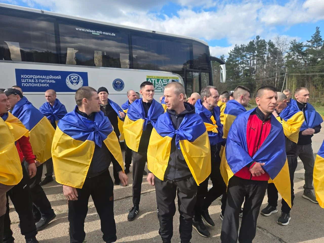 Звільнені цивільні з прапорами України біля автобуса координаційного штабу