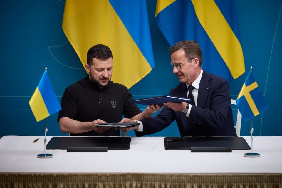Володимир Зеленський та премєр Швеції Ульф Крістерссон обмінюються документами на тлі прапорів