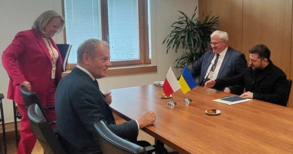 Дональд Туск і Володимир Зеленський за столом переговорів із прапорами Польщі та України