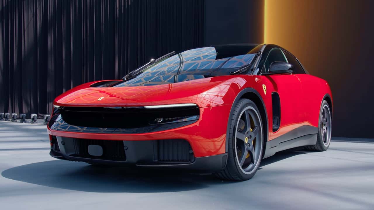 Червоний електромобіль Ferrari у студії на фоні темних штор