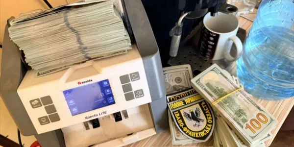 Лічильник купюр із пачками грошей, долари США та шеврон поліції біля кавоварки