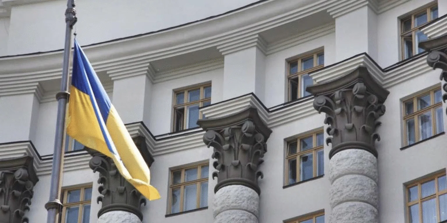 Український прапор майорить перед білою будівлею з колонами