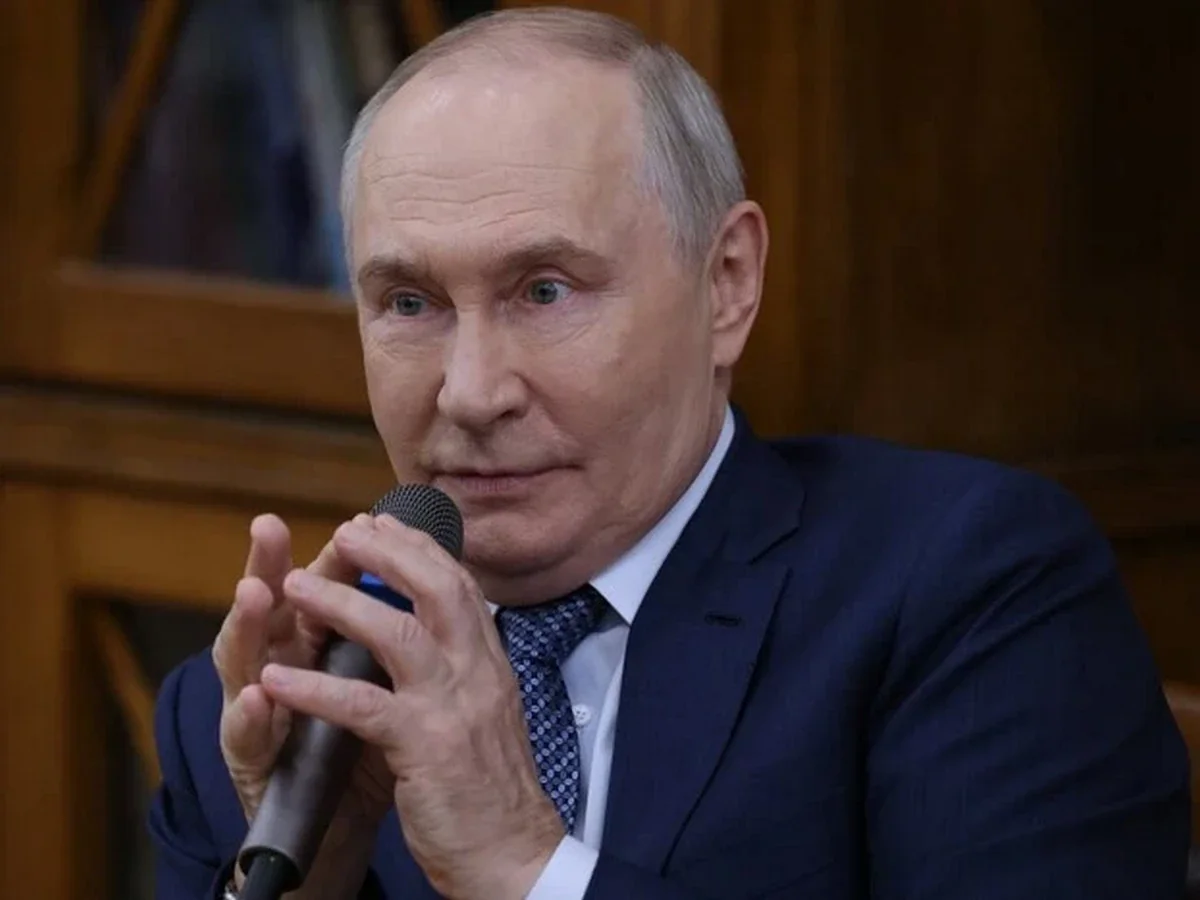 Володимир Путін у костюмі тримає мікрофон і виступає
